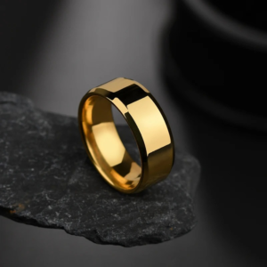 A gold standard stainless ring placed on a small black stone with a glossy black background